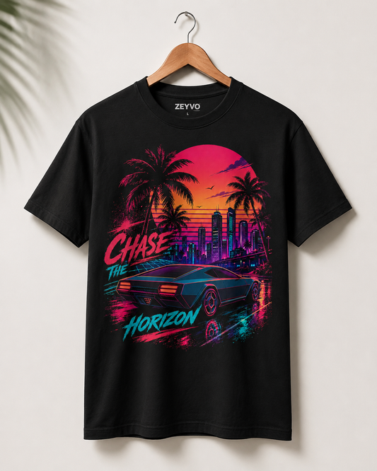 A black short-sleeve graphic t-shirt hanging on a wooden hanger against a light beige wall. The shirt features a vibrant, colorful retro-futuristic graphic with the text 'Chase the Horizon' and a neon car, sunset, and palm tree design.